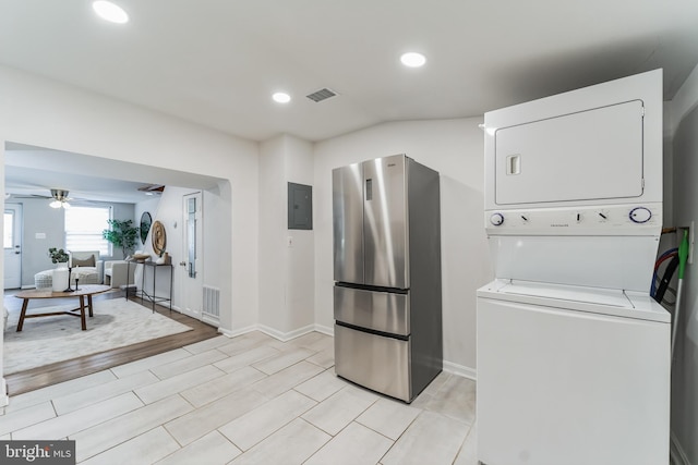 clothes washing area featuring ceiling fan, light wood-type flooring, stacked washer and dryer, and electric panel