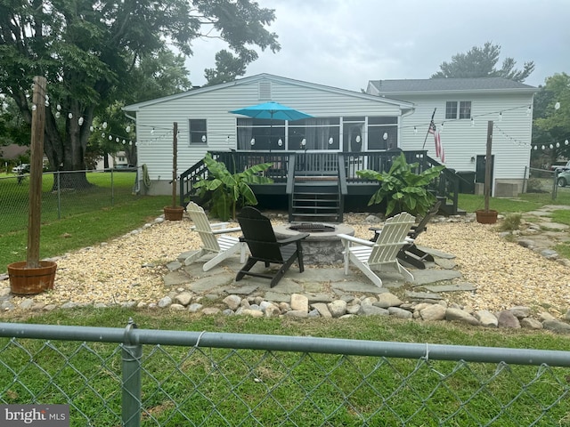 back of property with a wooden deck, a patio, and a fire pit