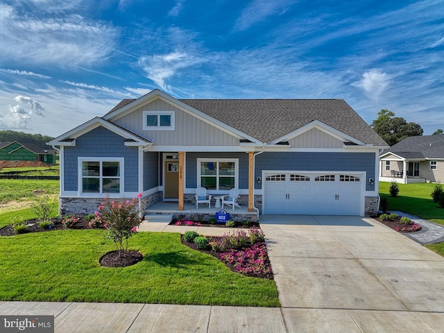 craftsman inspired home featuring stone siding, covered porch, driveway, and a front lawn