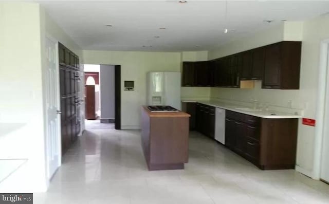 kitchen featuring white appliances, baseboards, a sink, and a center island