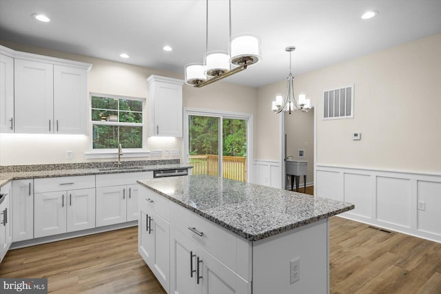 kitchen featuring a kitchen island, a sink, visible vents, and white cabinets