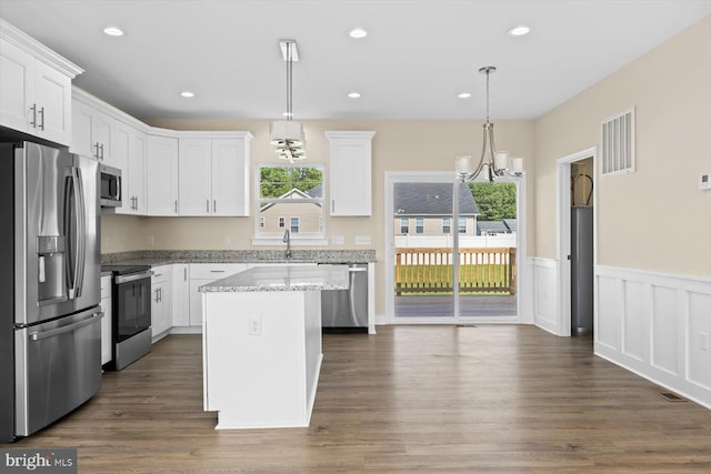 kitchen with a center island, stainless steel appliances, pendant lighting, and dark hardwood / wood-style flooring