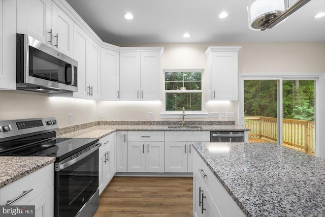 kitchen featuring appliances with stainless steel finishes, dark wood finished floors, white cabinetry, and a sink