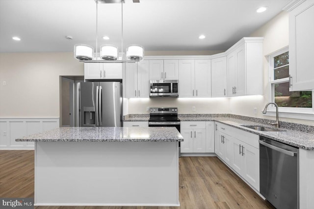 kitchen with a center island, stainless steel appliances, light wood-style flooring, white cabinets, and a sink