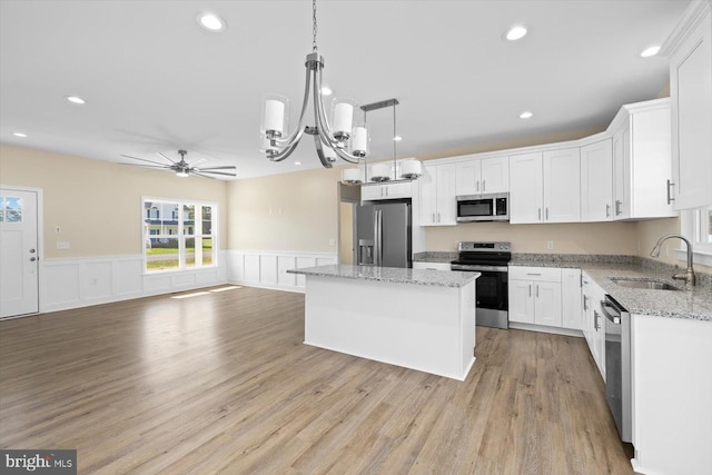 kitchen featuring a kitchen island, white cabinets, light hardwood / wood-style floors, sink, and stainless steel appliances