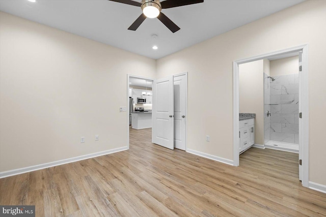 unfurnished bedroom featuring freestanding refrigerator, baseboards, connected bathroom, and light wood finished floors