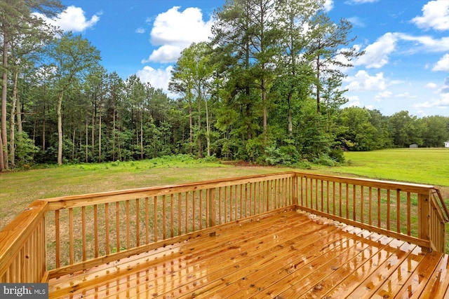 deck featuring a lawn and a view of trees