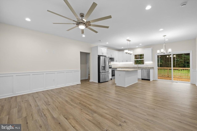 kitchen featuring a center island, ceiling fan with notable chandelier, stainless steel appliances, and open floor plan