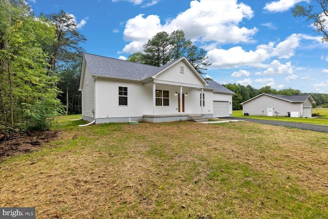 modern farmhouse featuring an attached garage, a front lawn, a porch, and roof with shingles