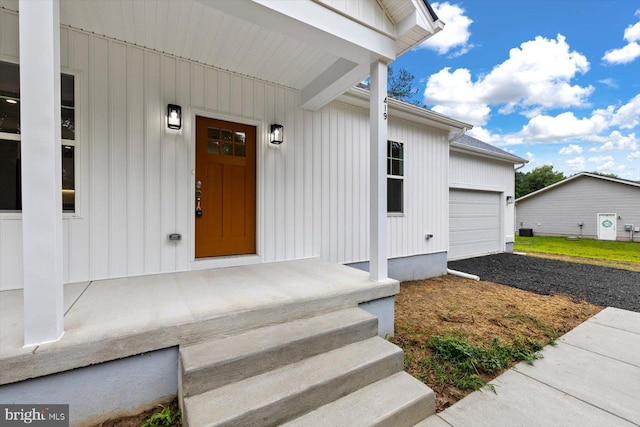 view of exterior entry featuring board and batten siding and gravel driveway