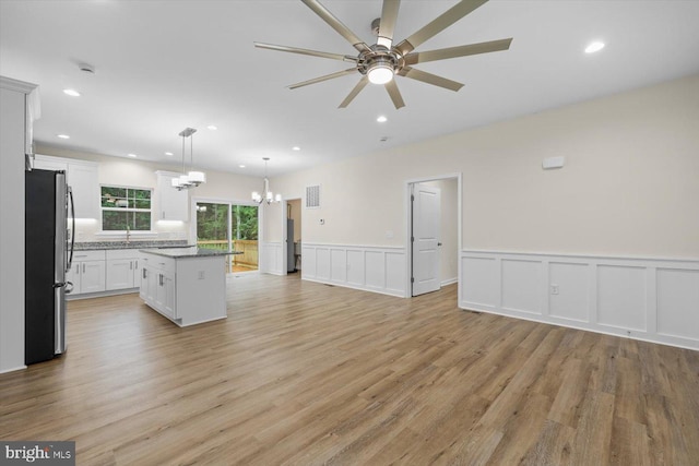 kitchen with a kitchen island, ceiling fan with notable chandelier, open floor plan, and freestanding refrigerator