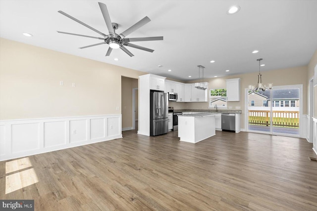 kitchen with appliances with stainless steel finishes, white cabinetry, light wood-type flooring, pendant lighting, and a kitchen island