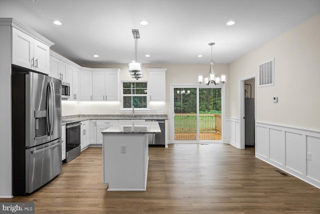 kitchen featuring appliances with stainless steel finishes, white cabinetry, a kitchen island, and visible vents