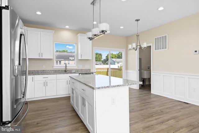 kitchen with decorative light fixtures, white cabinetry, stainless steel refrigerator with ice dispenser, wood-type flooring, and a center island