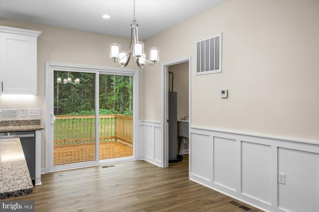 unfurnished dining area with visible vents, a chandelier, and wood finished floors