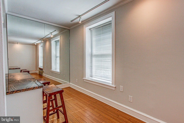 dining space featuring light hardwood / wood-style flooring, rail lighting, and ornamental molding