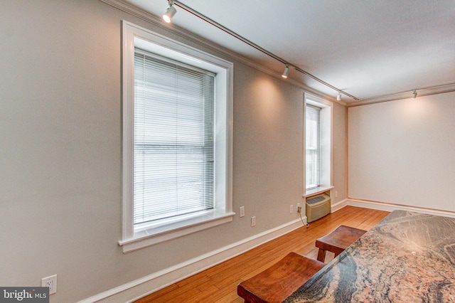 living room with light wood-type flooring, track lighting, and ornamental molding