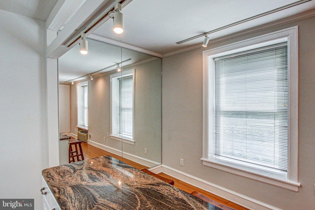 interior space featuring hardwood / wood-style flooring, rail lighting, and crown molding