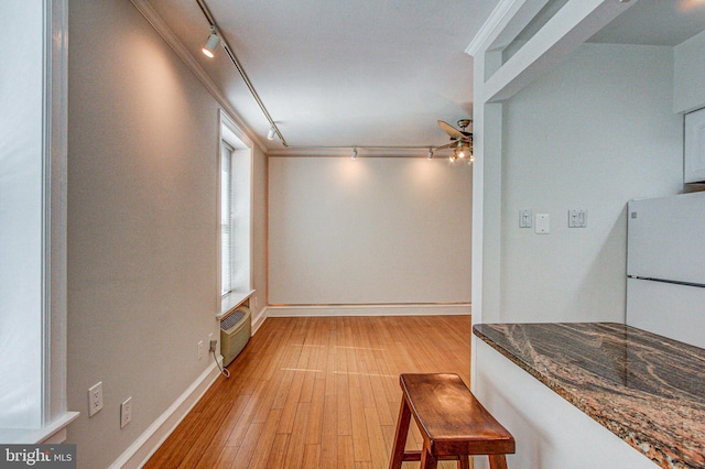 dining area featuring an AC wall unit, crown molding, light wood-type flooring, and track lighting