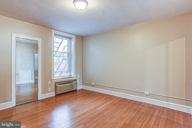 spare room with a wall mounted AC and hardwood / wood-style flooring