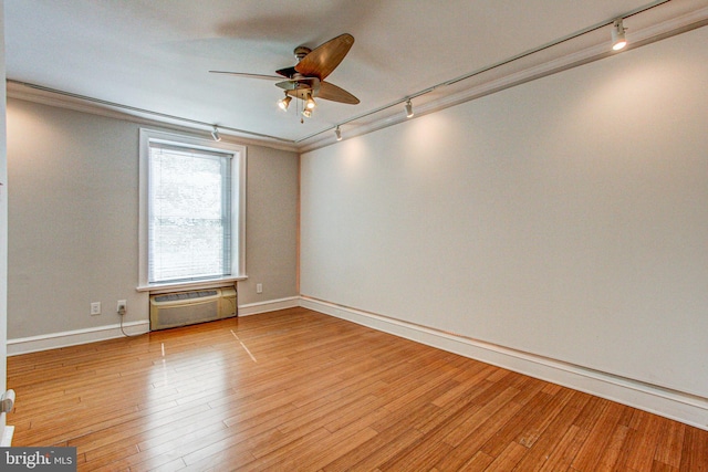 empty room with a wall unit AC, light hardwood / wood-style flooring, rail lighting, ceiling fan, and ornamental molding