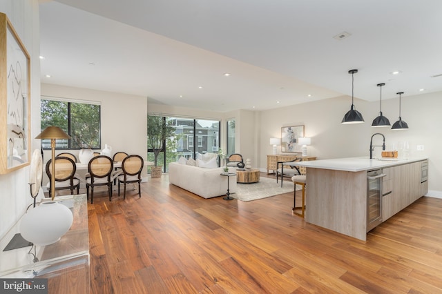 living room with wine cooler, sink, and light hardwood / wood-style floors