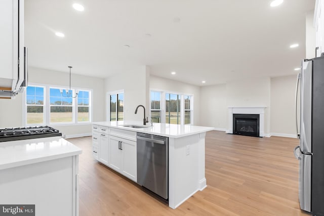 kitchen with a wealth of natural light, hanging light fixtures, an island with sink, and stainless steel appliances