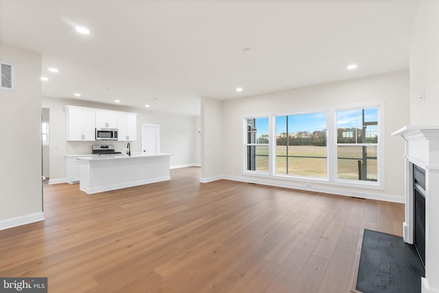 unfurnished living room with sink and light hardwood / wood-style flooring