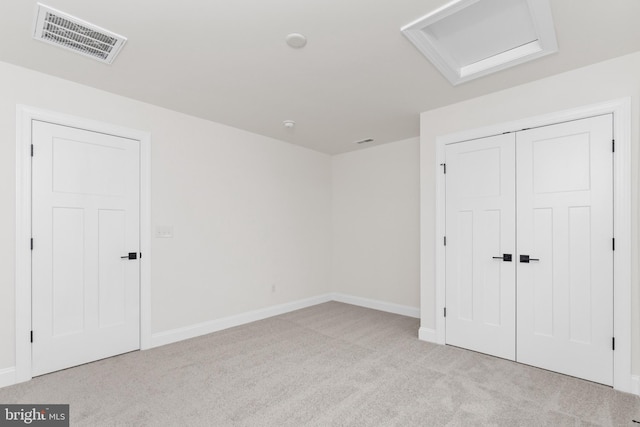 unfurnished bedroom featuring light colored carpet and a closet