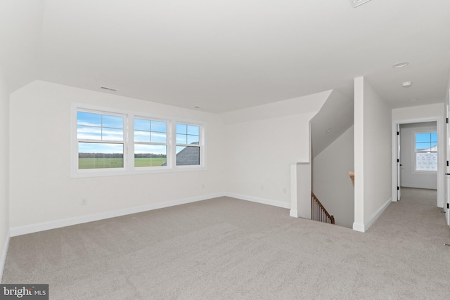 bonus room with a wealth of natural light, lofted ceiling, and light colored carpet