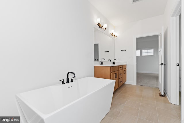 bathroom with a washtub, vanity, and tile patterned floors