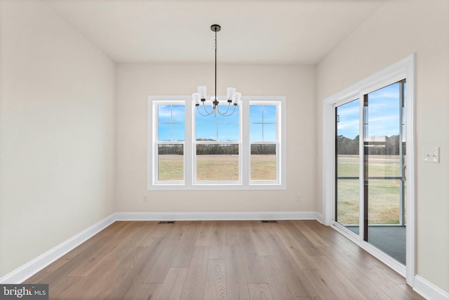 unfurnished dining area featuring light wood-type flooring and a notable chandelier