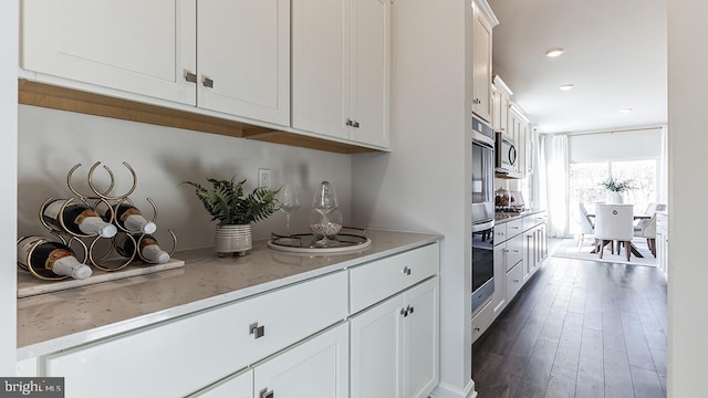 kitchen with white cabinetry, light stone countertops, dark hardwood / wood-style flooring, and appliances with stainless steel finishes