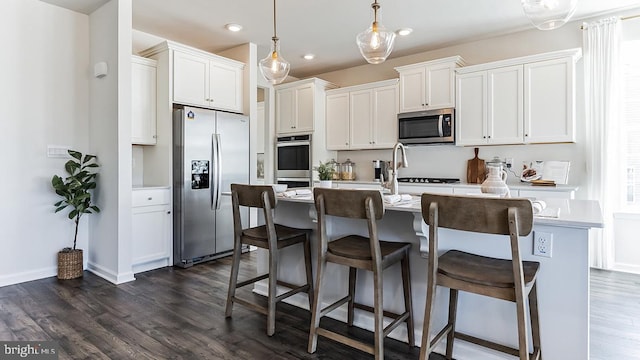 kitchen with a kitchen island with sink, white cabinets, dark hardwood / wood-style floors, and stainless steel appliances