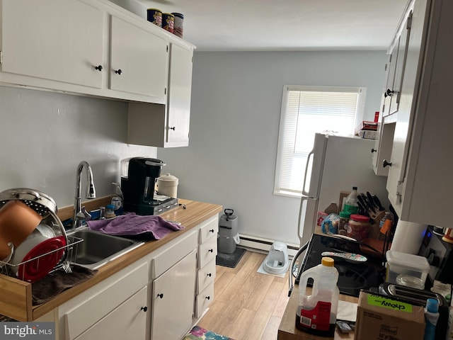 kitchen featuring sink, white cabinets, white refrigerator, baseboard heating, and light hardwood / wood-style flooring