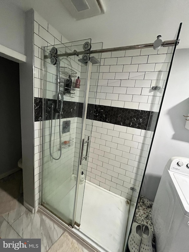 bathroom featuring washer / dryer and an enclosed shower