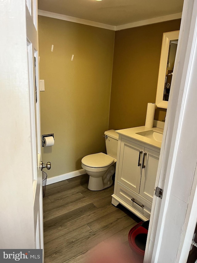 bathroom featuring hardwood / wood-style flooring, vanity, toilet, and crown molding