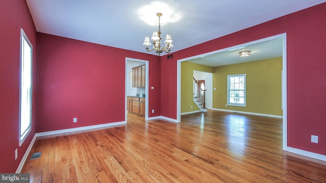 empty room featuring wood-type flooring and a chandelier