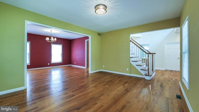 spare room featuring a notable chandelier and dark wood-type flooring