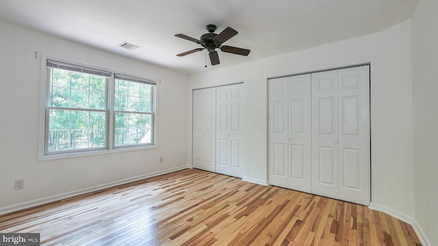 unfurnished bedroom featuring light hardwood / wood-style floors, two closets, and ceiling fan