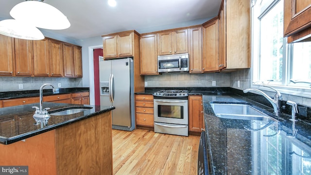 kitchen featuring sink, appliances with stainless steel finishes, light wood-type flooring, and backsplash