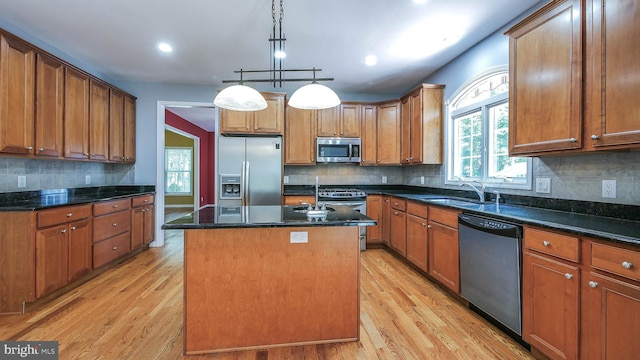 kitchen featuring decorative backsplash, light hardwood / wood-style floors, appliances with stainless steel finishes, and a kitchen island