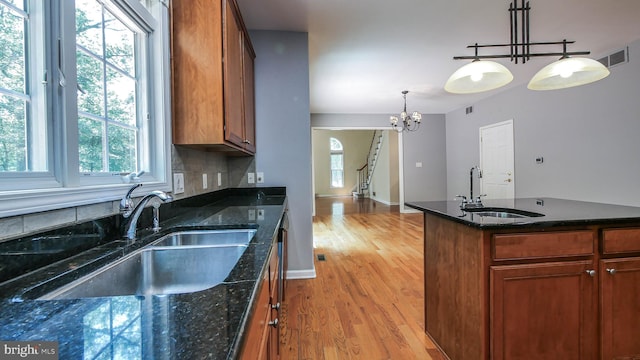 kitchen featuring sink, a chandelier, pendant lighting, and light hardwood / wood-style floors