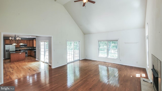 living room featuring ceiling fan with notable chandelier, a fireplace, hardwood / wood-style flooring, and high vaulted ceiling