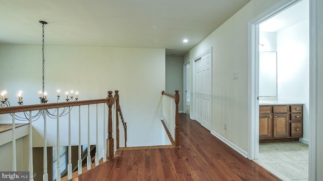 corridor with a notable chandelier and hardwood / wood-style floors