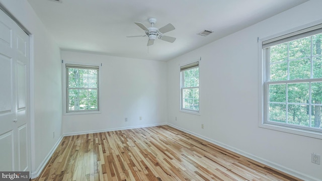 unfurnished room featuring light wood-type flooring, a wealth of natural light, and ceiling fan