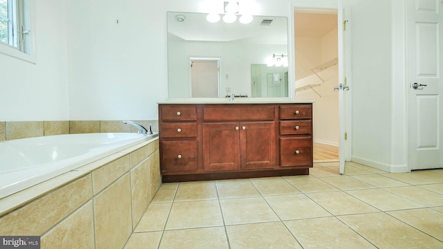 bathroom with tiled tub, vanity, and tile patterned flooring