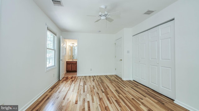 unfurnished bedroom featuring light hardwood / wood-style floors, connected bathroom, multiple windows, and ceiling fan