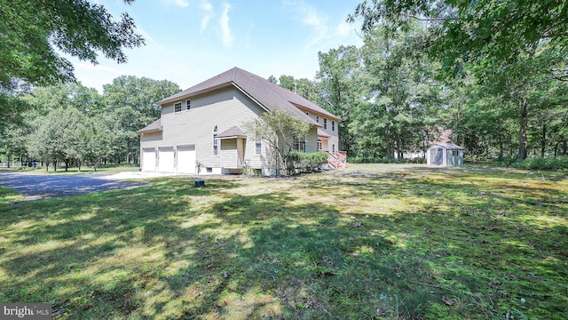 view of side of home featuring a storage unit, a garage, and a lawn