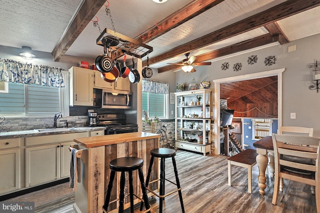 kitchen featuring beam ceiling, tasteful backsplash, ceiling fan, range with electric stovetop, and sink